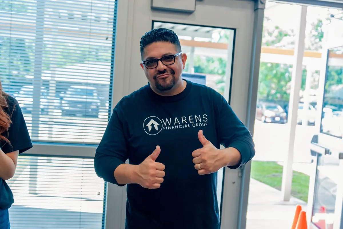 A Warens Financial Group team member giving two thumbs up at the drive